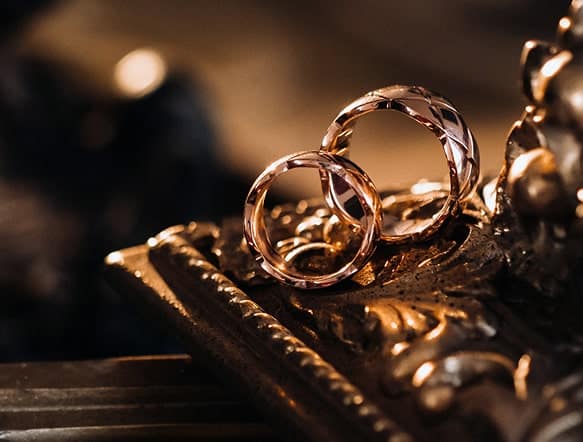 a pair of gold wedding rings lie on a golden antique jewelry box